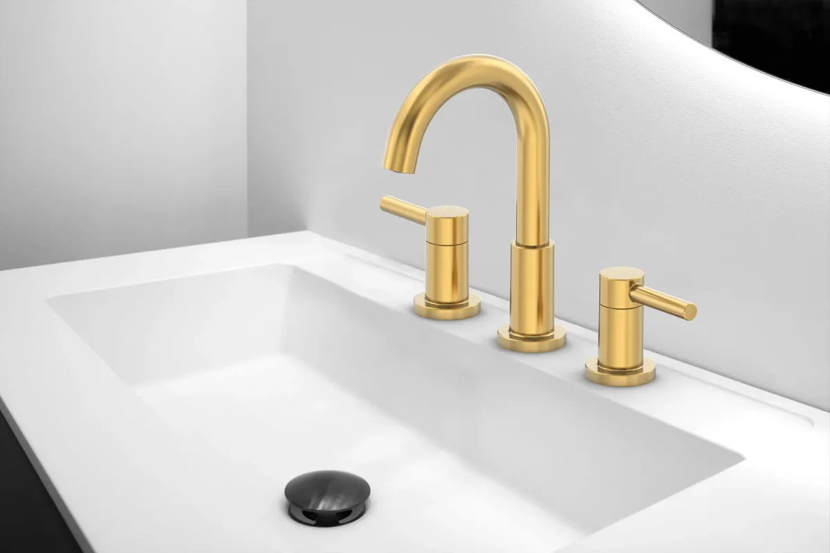 Brushed gold widespread bathroom faucet with two lever handles and an arched spout on a white undermount sink