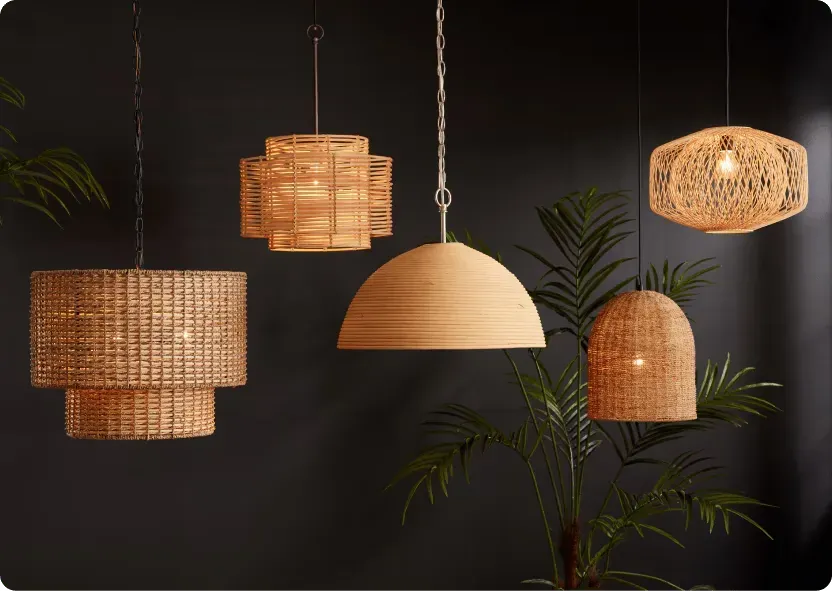 Three woven rattan pendant lights in different shapes hung at staggered heights against a dark wall